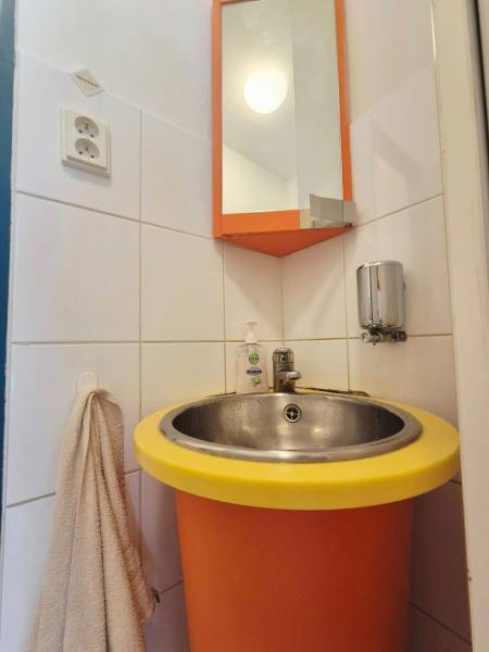 Orange sink with a round yellow rim, mirror, and towel rack.