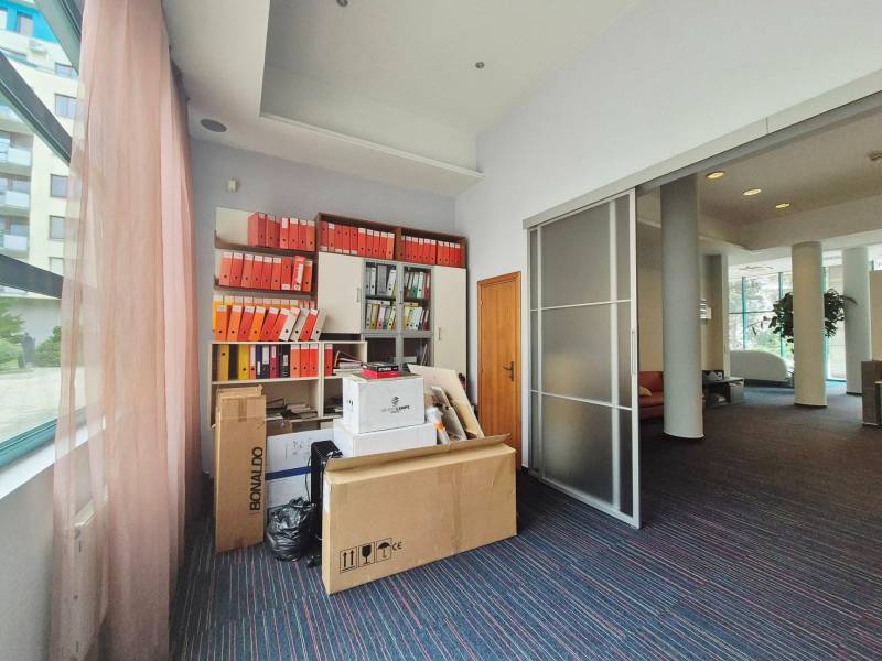 Office space with filing cabinets and packages in the office, illuminated by large windows.