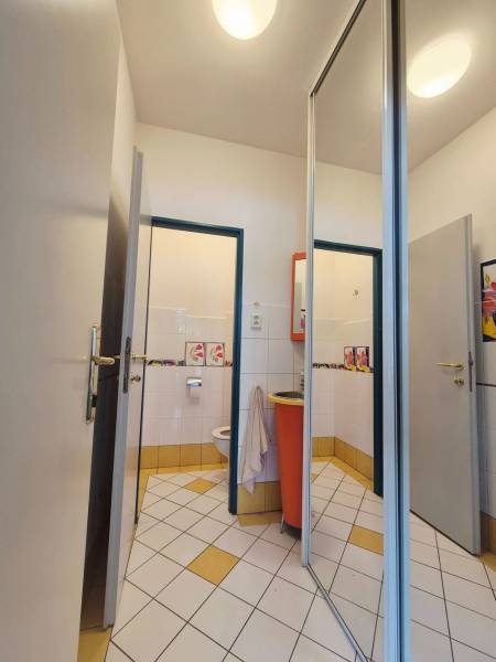 A restroom with white and yellow tiles and an orange sink in a commercial space.