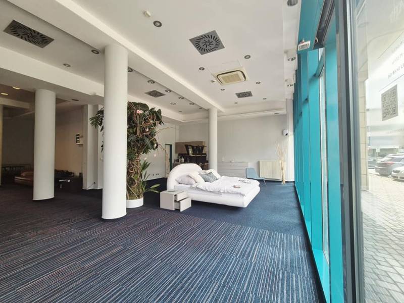 Commercial space with a bed, high columns, and large windows.
