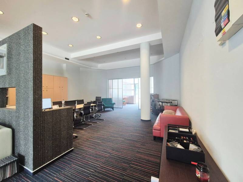 Commercial space with a conference table, red sofa, and modern furniture.