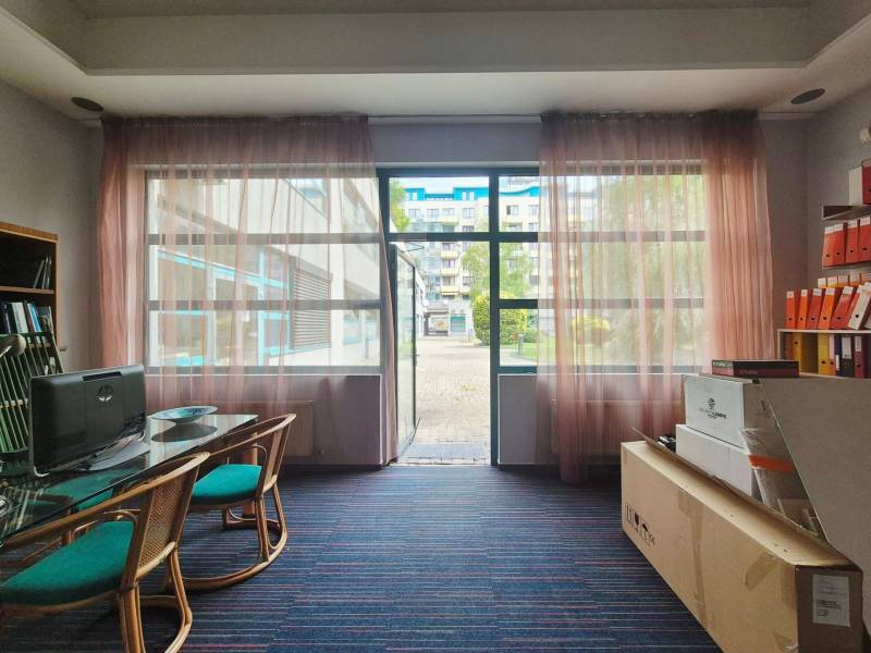 Commercial premises with a glass wall, a computer, a desk, and a shelf with binders.