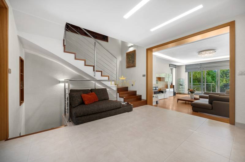 Interior of a family house with a sofa, staircase, and spacious living room with a terrace.