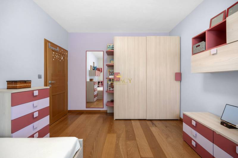 Children's room in a family house with pink and purple dressers, a mirror, and wooden flooring.