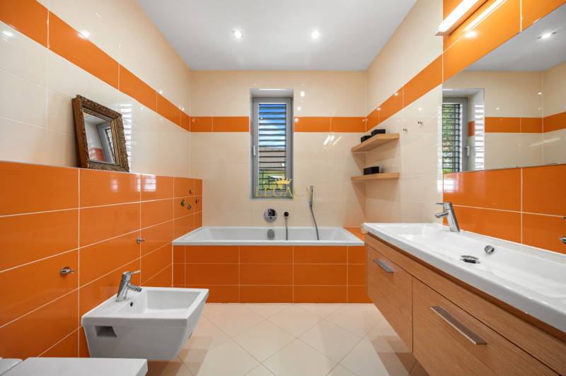 A bathroom in a family house with orange-beige tiles, a bathtub, a sink, and a bidet.