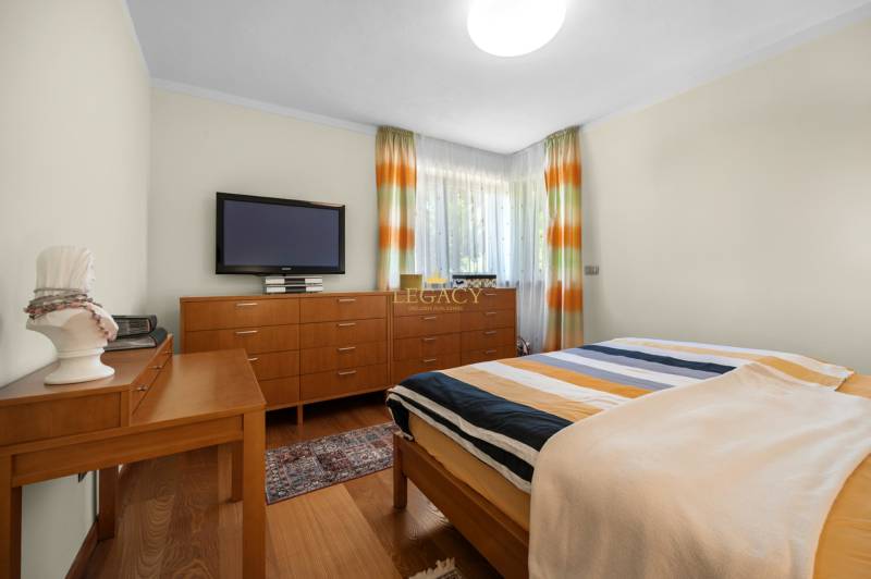 A bedroom in a family house with wooden furniture, a TV, and colorful curtains.