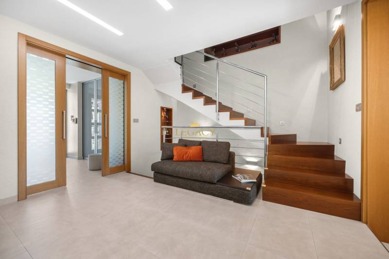A family house with wooden stairs, glass, and a sofa with a cushion.