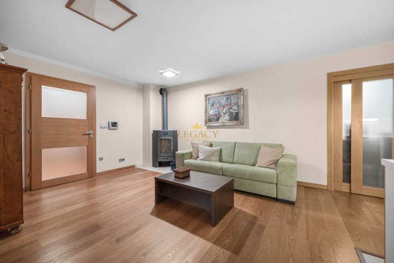Living room with wooden flooring, green sofa, and tiled fireplace in a family house.