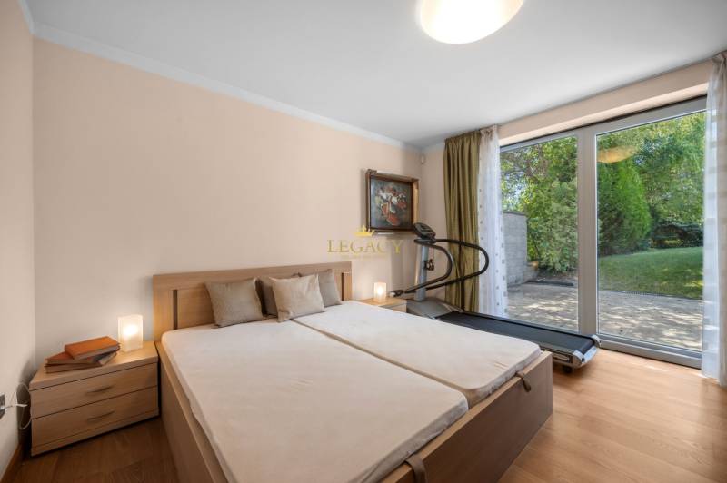 Bedroom in a family house with a double bed, treadmill, and garden view.