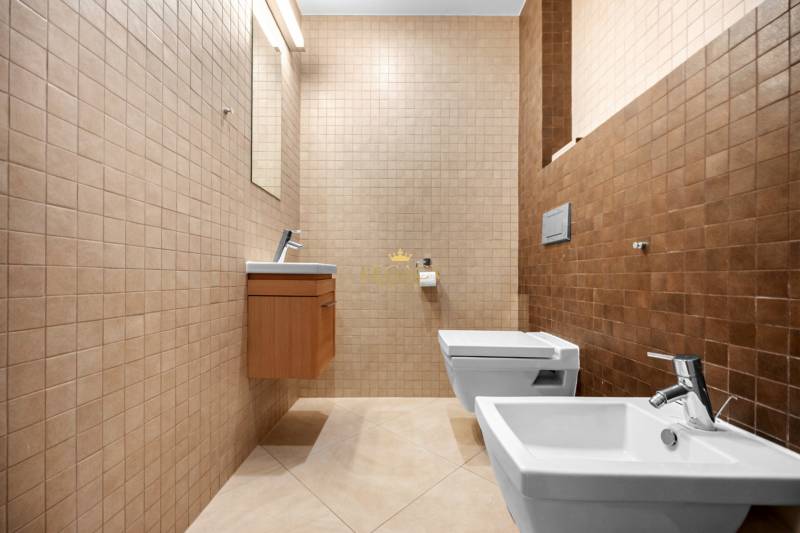 A bathroom in a family house with beige tiles, a bidet, and a wall-mounted toilet.