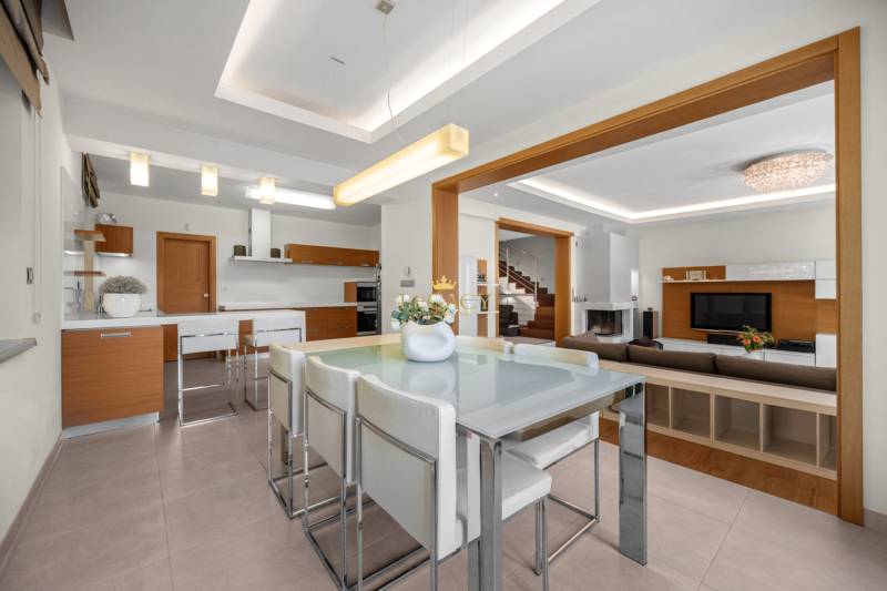 Interior of a family house with a dining table, kitchenette, living room, and staircase.
