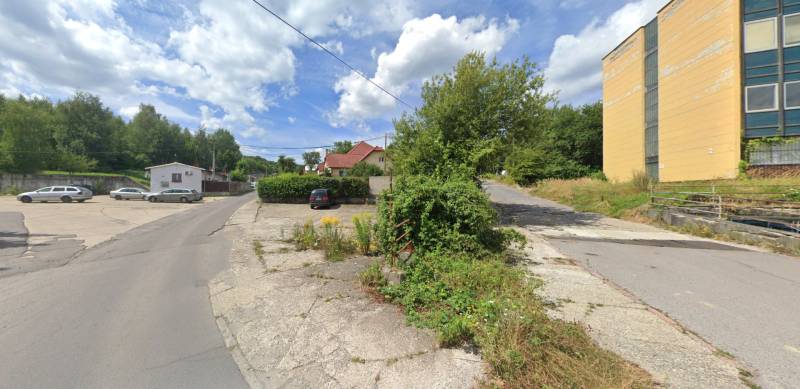 Commercial plots on Štrajková Street in Handlová, with greenery and parking.