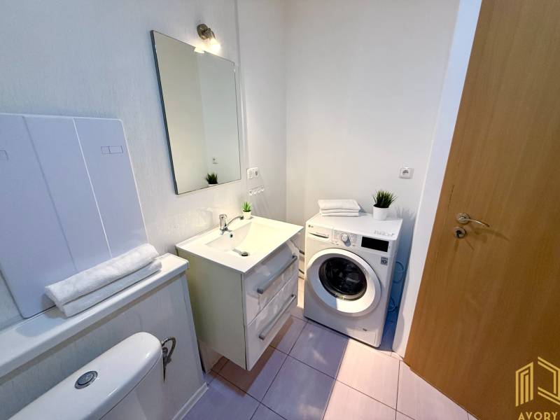 Bathroom in a 2-room apartment with a mirror, washing machine, and toilet.