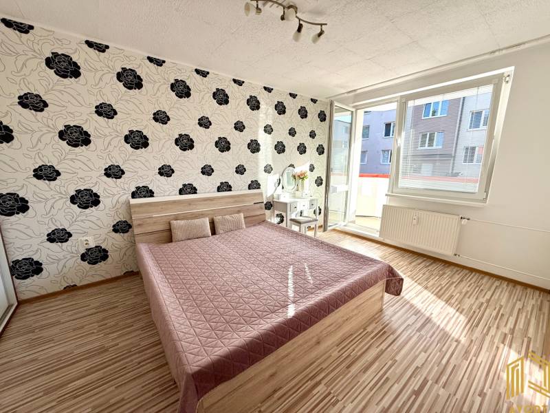 Bedroom in a two-room apartment with patterned wallpaper and a double bed.