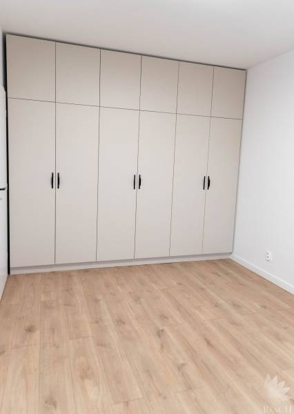 White built-in wardrobe with six doors in a 2-room apartment on a wooden floor.