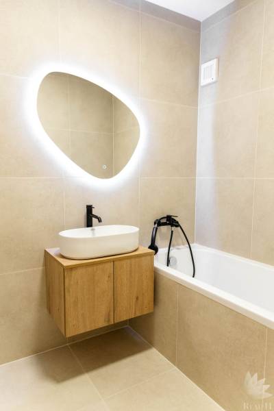 A bathroom in a 2-room apartment with an oval mirror and a bathtub.