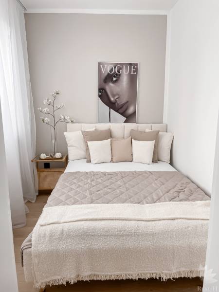 A bright, cozy bedroom in a 2-room apartment with a poster and decorative pillows.