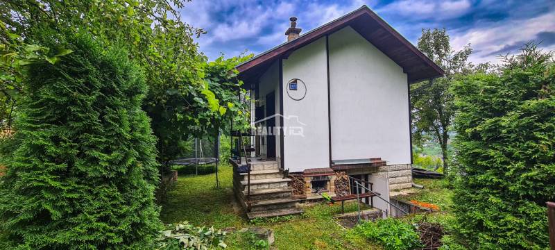 A cottage in Mojš surrounded by greenery, stairs leading to the entrance, a trampoline in the garden.