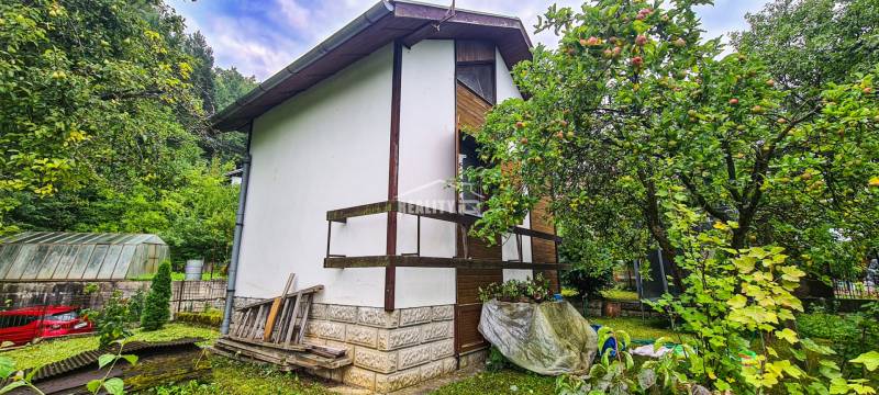 A cottage in Mojša surrounded by a green garden and fruit trees.
