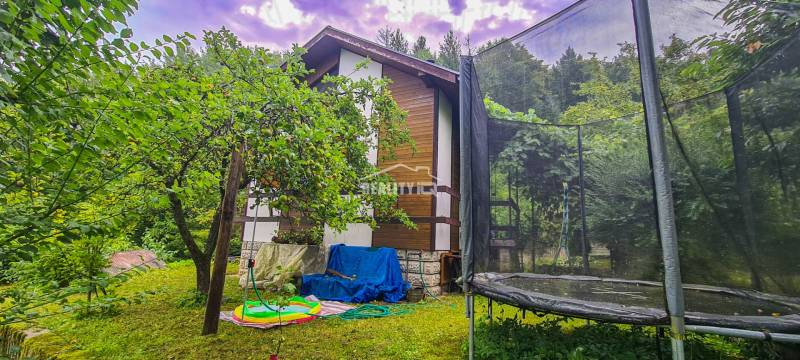 A cottage in Mojš surrounded by greenery, a garden with a trampoline, and a unique atmosphere.