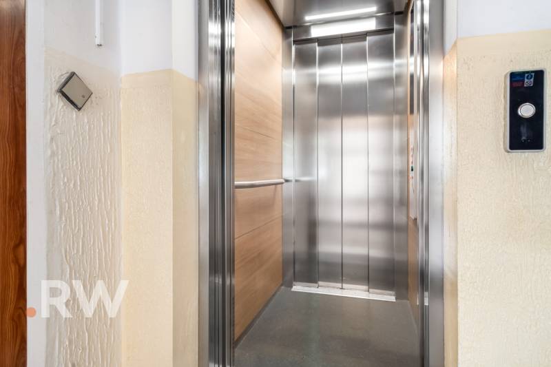 Opening a modern elevator on the floor of a residential building with a wooden decor.