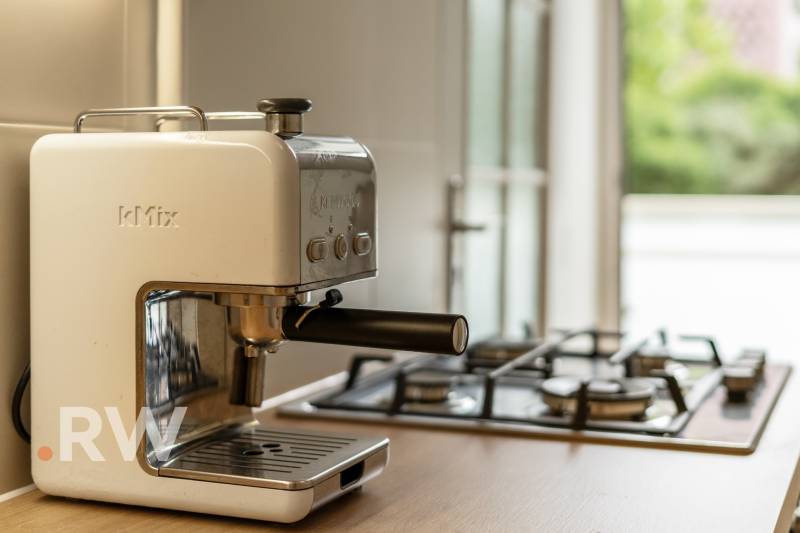 Coffee maker kMix and gas stove on the kitchen counter in a 2-room apartment.
