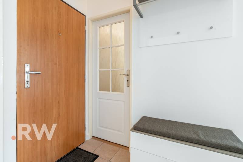 White interior with doors and a bench in a 2-room apartment.