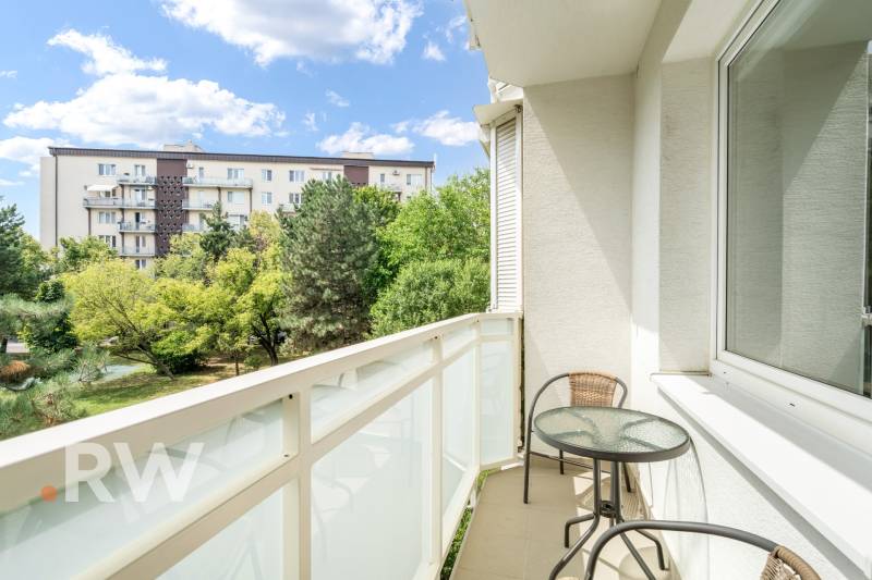 The balcony of the 2-room apartment offers a view of greenery and residential buildings in Bratislava.