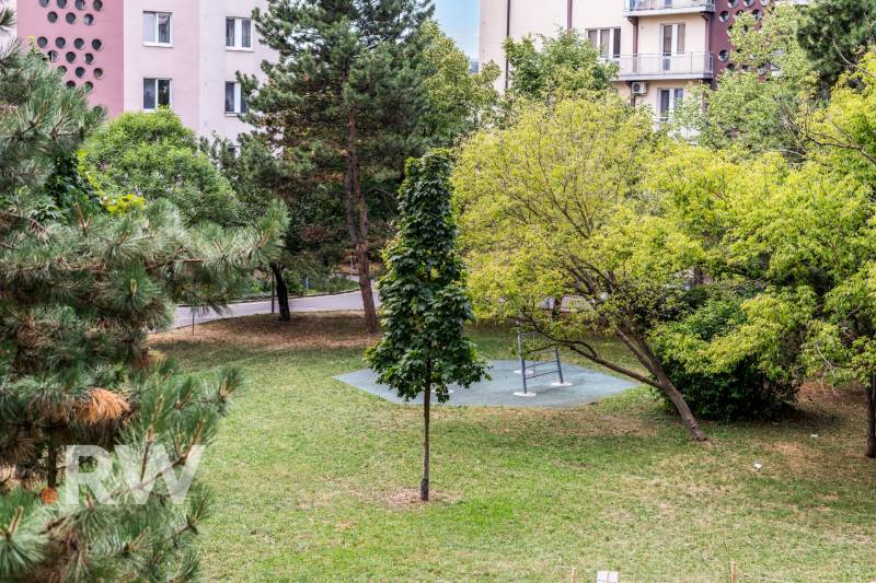 Park in Bratislava on Czechoslovak Paratroopers with a bench and greenery, surrounded by apartment buildings.