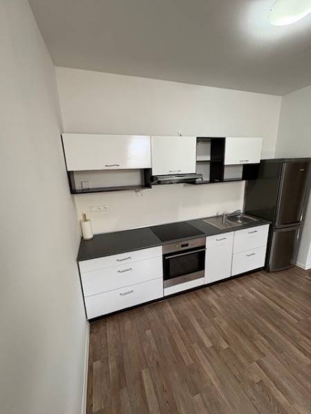 A kitchen in a 2-room apartment with white cabinets, a black countertop, and stainless steel appliances.