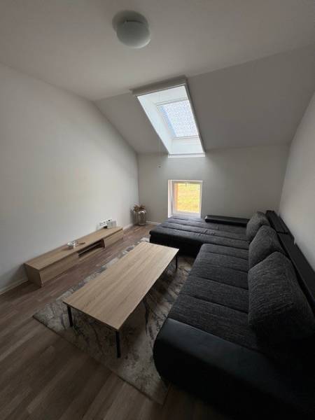 A living room in a two-room apartment with a sofa under a skylight and a coffee table.