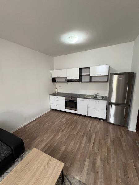 A kitchen in a 2-room apartment with a wooden floor and modern appliances.