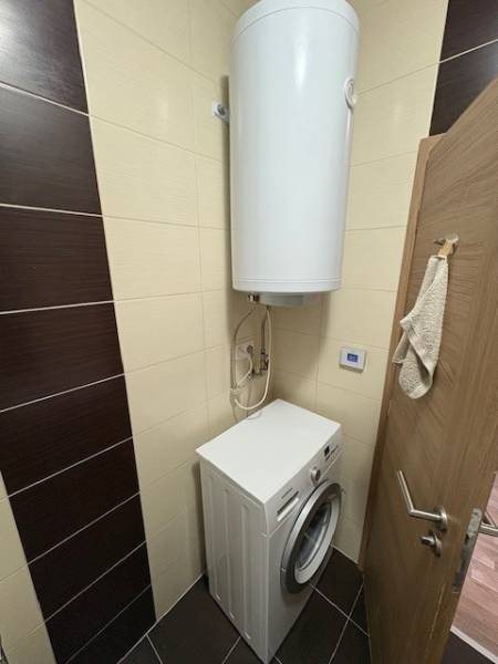 A washing machine with a water tank in the bathroom of a 2-room apartment.