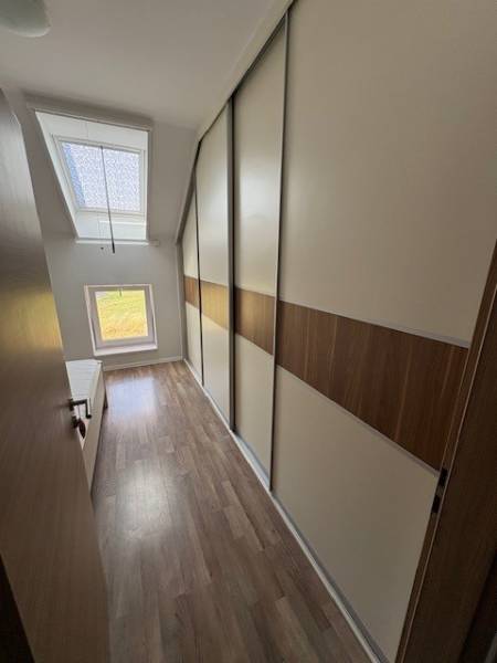 A narrow hallway with built-in wardrobes in a 2-room apartment with wooden flooring.