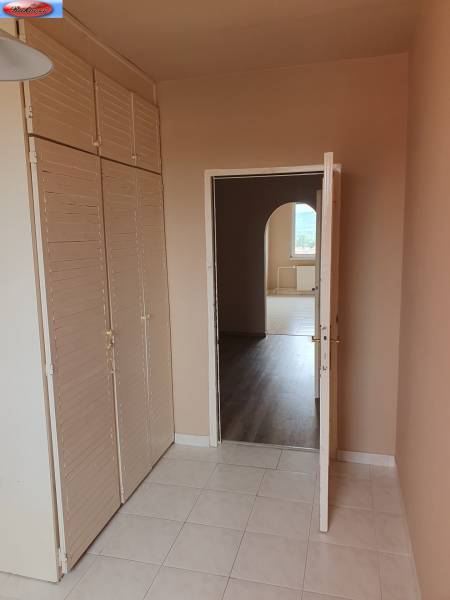 Interior of a 3-room apartment with tiles, a coat rack wall, and a passage to another room.