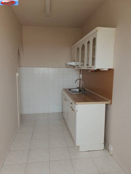 A kitchen with white cabinets and a sink in a 3-room apartment.
