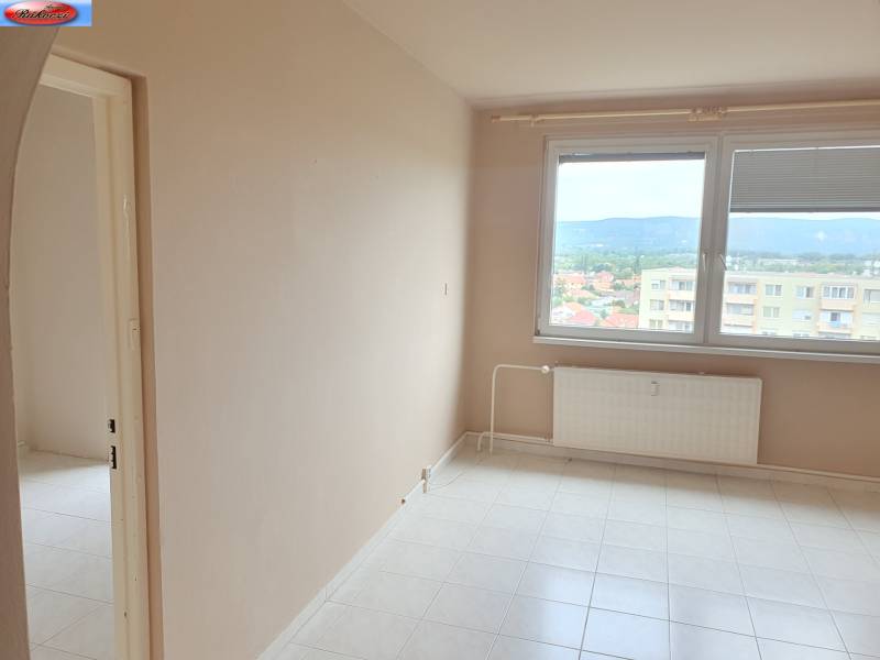 An empty room in a 3-room apartment, with a radiator under a large window.