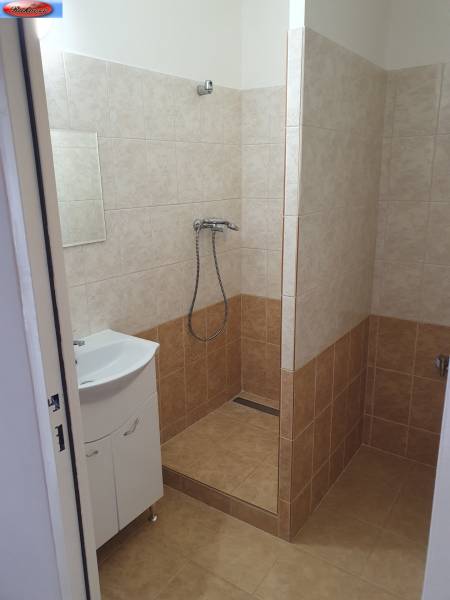 A bathroom of a three-room apartment with a bathtub and a sink, tiled with light ceramic tiles.