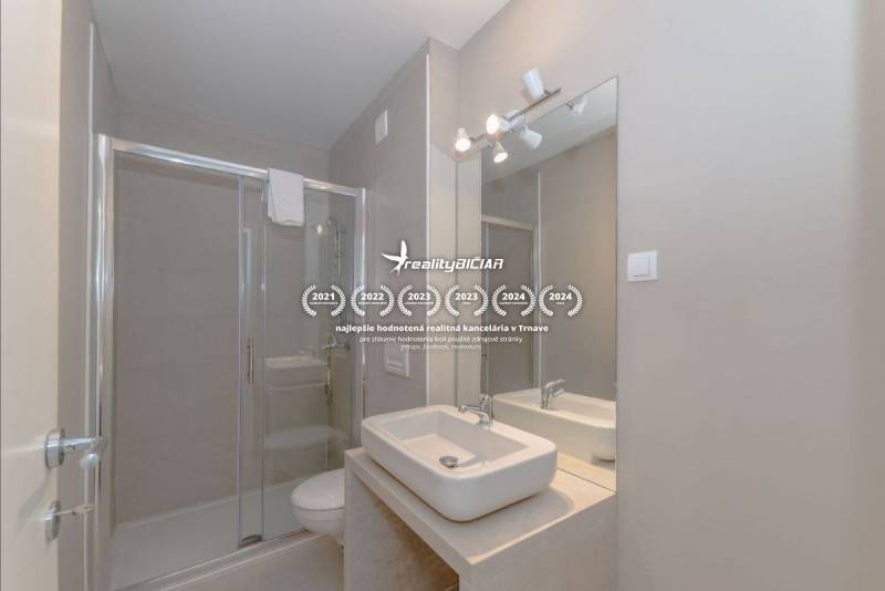 Bathroom of a holiday apartment with a sink, mirror, and shower.