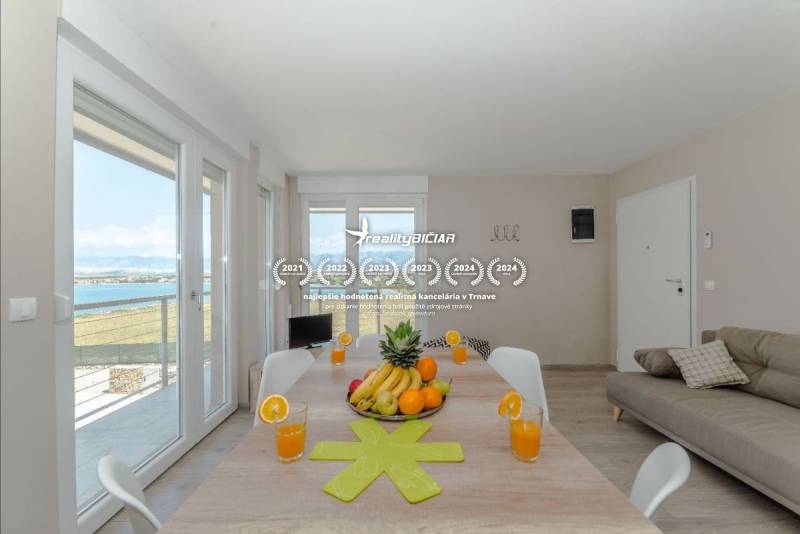 Recreational apartment with a large table, sea view, fruit, and glasses of juice.