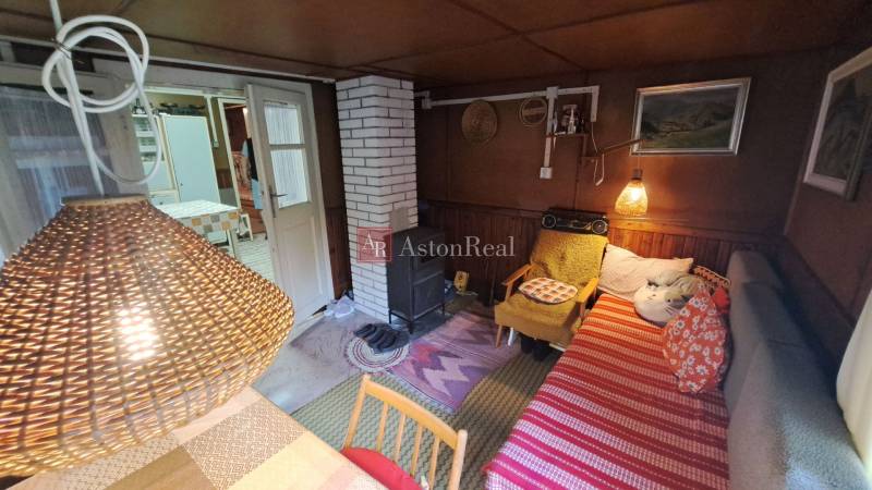 A cozy atmosphere in a cabin with a wood stove, a lamp, and a sofa with cushions.