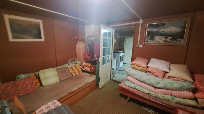 A cozy room in the cottage with a sofa, duvets, and pictures on the walls.