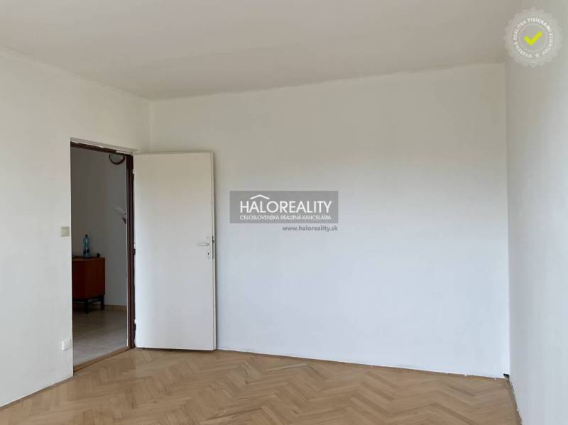 Empty room with a white wall and wooden floor in a 3-room apartment.