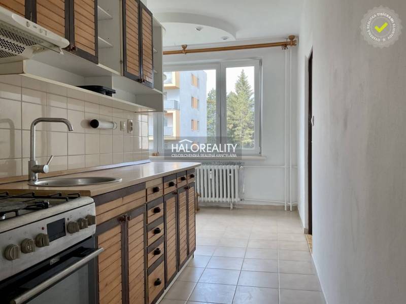 A kitchen in a 3-room apartment with a wooden cabinet, stove, and a window with a radiator.