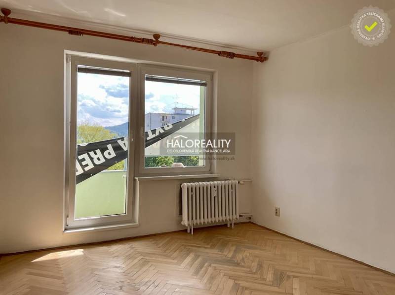 A room with parquet floors and a large window in a three-room apartment.