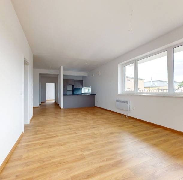 Spacious living area with wooden flooring in a 3-room apartment.