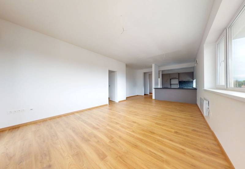 A spacious room with wooden flooring and a kitchenette in a 3-room apartment.