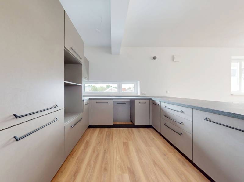 A kitchen in a 3-room apartment with light cabinets and wooden floors.