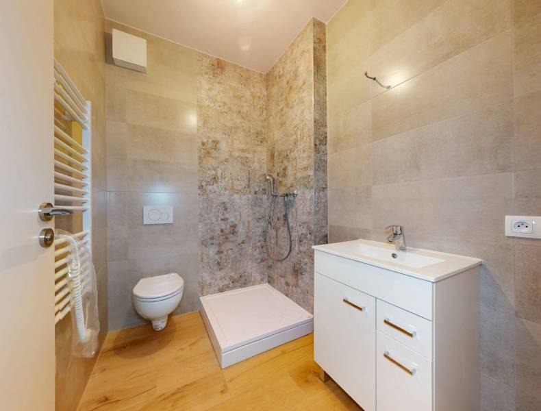 A bathroom in a 3-room apartment with a toilet, shower, and sink.