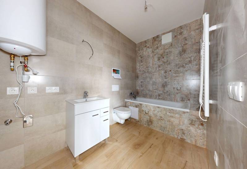 Bathroom in a 3-room apartment with a bathtub, sink, and wall-hung toilet.